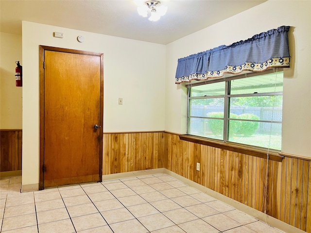 tiled spare room featuring wooden walls