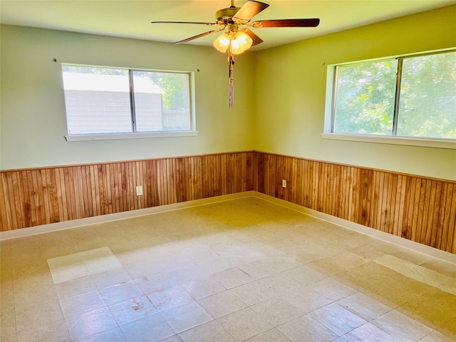 unfurnished room featuring ceiling fan and wood walls