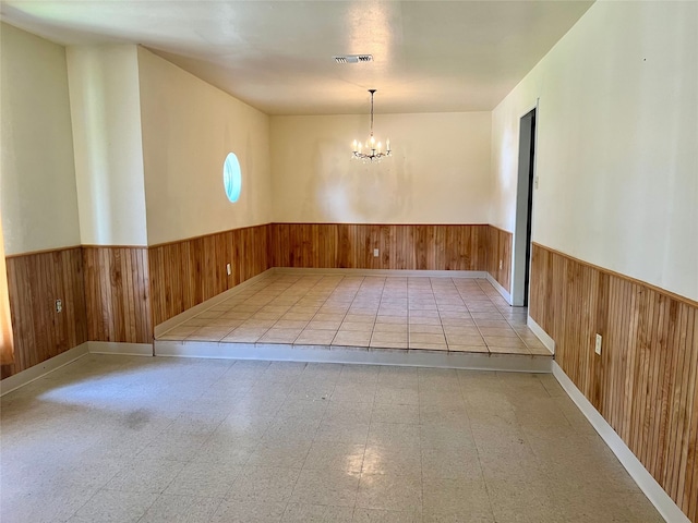 empty room with a chandelier and wood walls