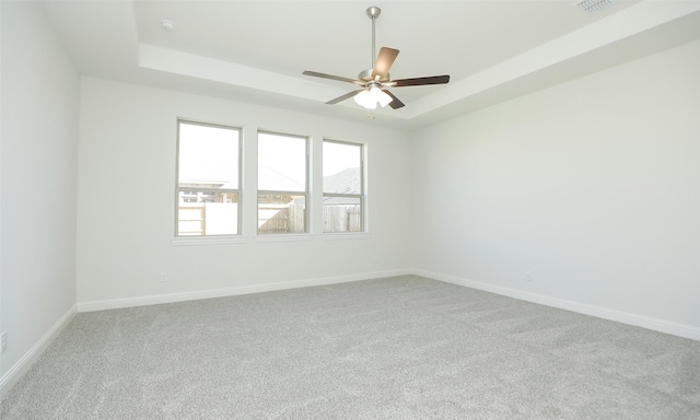 carpeted spare room with a tray ceiling and ceiling fan