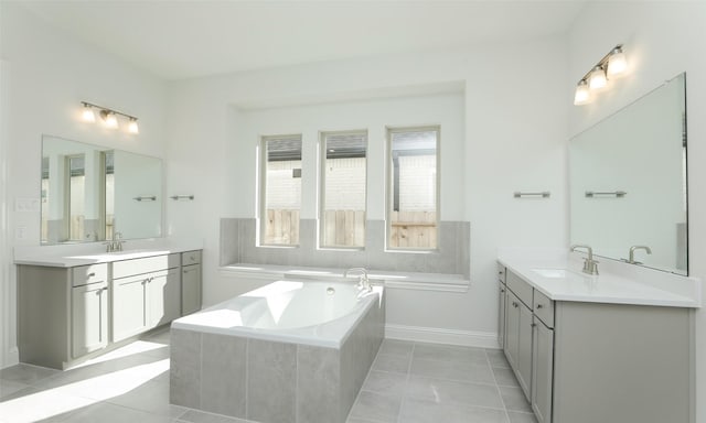 bathroom with tile patterned floors, vanity, and a relaxing tiled tub