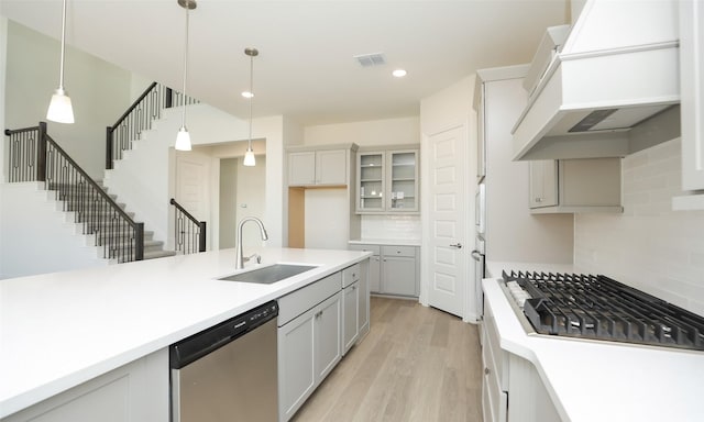 kitchen featuring premium range hood, decorative backsplash, sink, and stainless steel dishwasher