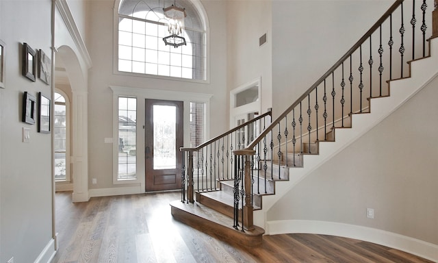 entryway featuring a notable chandelier, light hardwood / wood-style flooring, and a towering ceiling