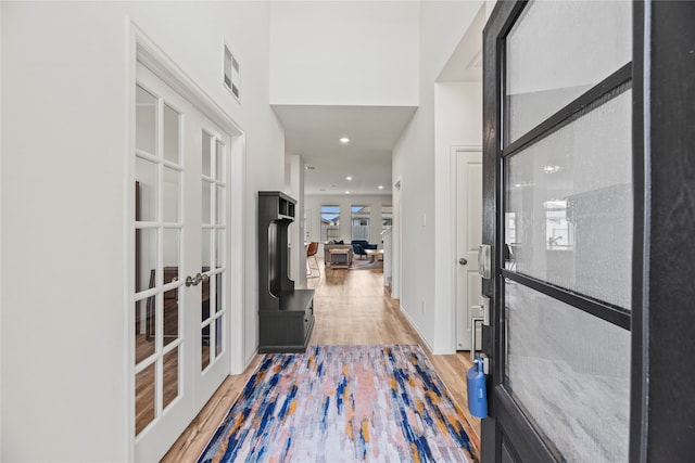 hall with light wood-type flooring and french doors