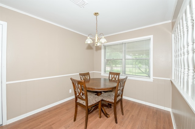 dining space with a chandelier, light wood-type flooring, and ornamental molding