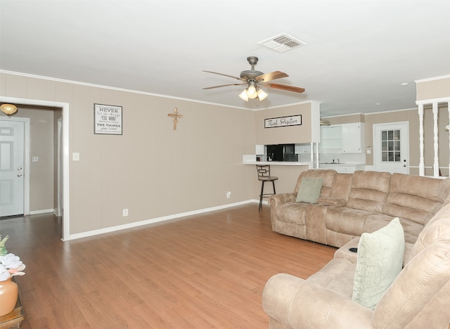 living room featuring ornamental molding, light hardwood / wood-style flooring, and ceiling fan