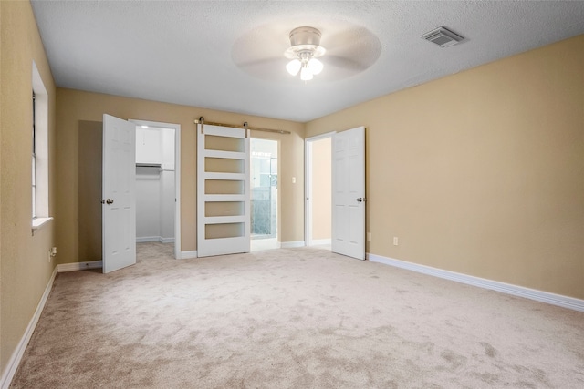 unfurnished bedroom featuring a closet, a textured ceiling, ceiling fan, and light colored carpet