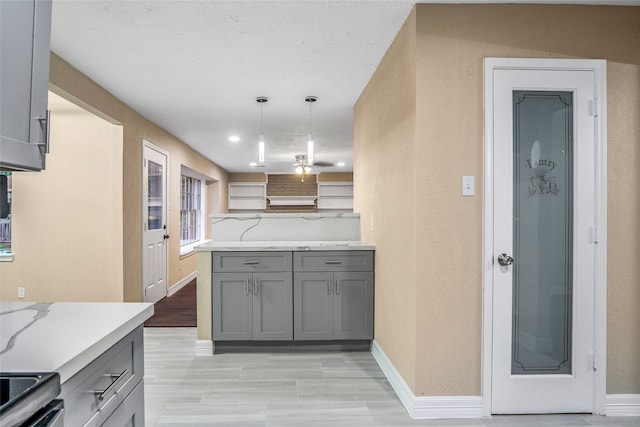 kitchen featuring stove, pendant lighting, kitchen peninsula, gray cabinets, and light wood-type flooring