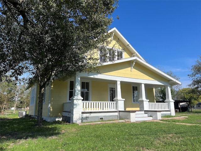 view of front of home with cooling unit, covered porch, and a front lawn