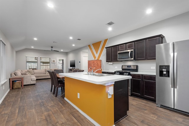 kitchen with ceiling fan, an island with sink, sink, appliances with stainless steel finishes, and dark wood-type flooring