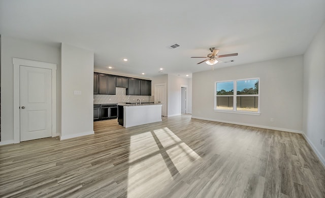 unfurnished living room with ceiling fan, sink, and light hardwood / wood-style flooring