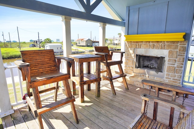 wooden deck featuring a bar and an outdoor stone fireplace