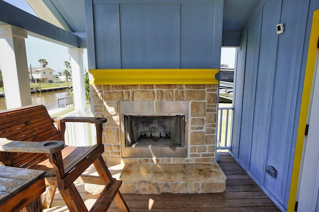 exterior space with a fireplace, dark hardwood / wood-style flooring, a water view, and a wealth of natural light