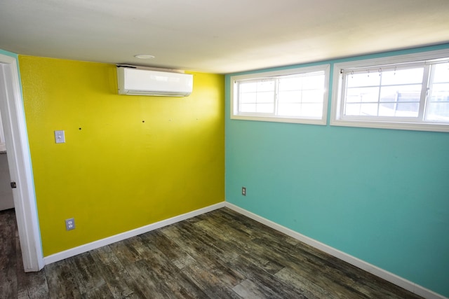 basement featuring a healthy amount of sunlight, dark hardwood / wood-style floors, and a wall unit AC