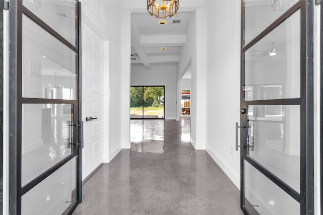 hall with beamed ceiling, concrete floors, and an inviting chandelier