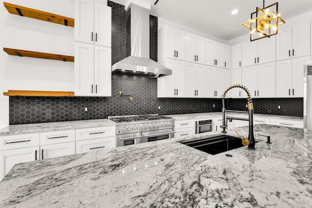 kitchen with light stone countertops, backsplash, range with two ovens, and wall chimney range hood