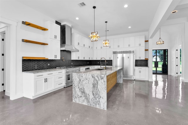 kitchen with high end appliances, sink, light stone countertops, an island with sink, and white cabinetry