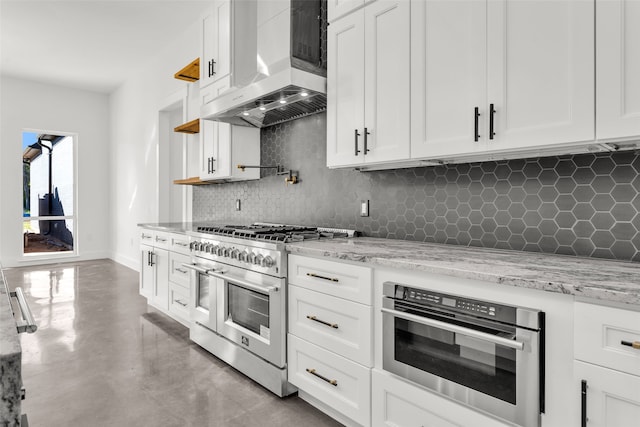 kitchen featuring light stone countertops, tasteful backsplash, wall chimney exhaust hood, stainless steel appliances, and white cabinets