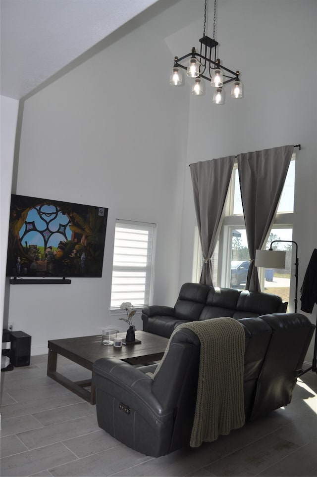 living room featuring an inviting chandelier, plenty of natural light, and high vaulted ceiling