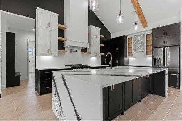 kitchen featuring light hardwood / wood-style floors, lofted ceiling, stainless steel fridge with ice dispenser, and a kitchen island with sink