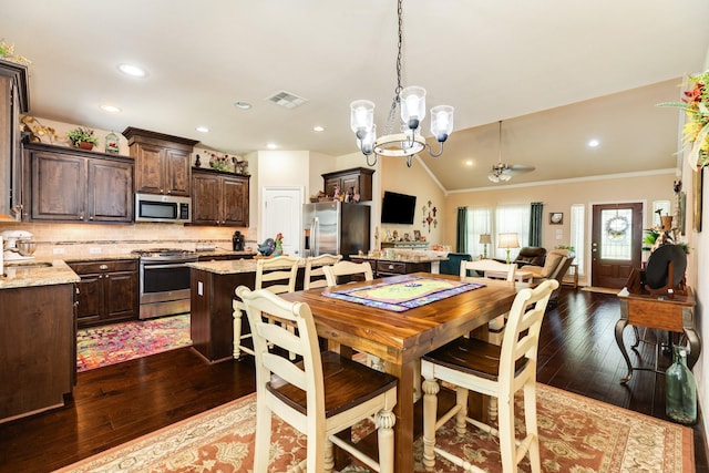 dining room with dark wood-type flooring, ornamental molding, sink, and vaulted ceiling