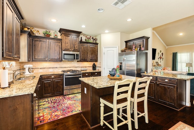 kitchen featuring a kitchen island, appliances with stainless steel finishes, dark hardwood / wood-style floors, and sink