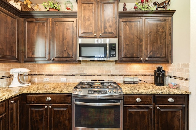 kitchen with backsplash, dark brown cabinetry, appliances with stainless steel finishes, and light stone counters