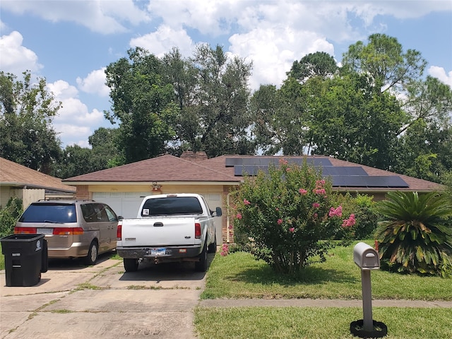 view of front of home featuring solar panels, a garage, and a front yard