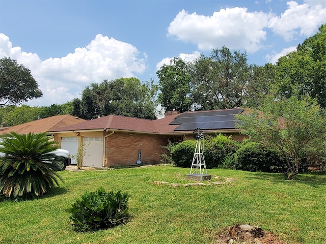 single story home featuring a garage, solar panels, and a front yard