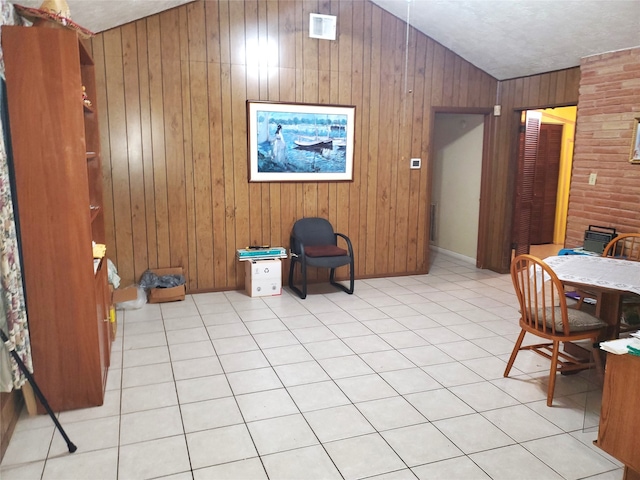 interior space featuring lofted ceiling, wood walls, and light tile patterned floors