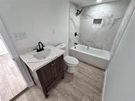 full bathroom featuring tiled shower / bath combo, toilet, and vanity