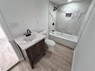 full bathroom featuring vanity, toilet, tiled shower / bath combo, and wood-type flooring