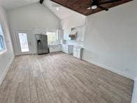 unfurnished living room featuring beam ceiling, high vaulted ceiling, and light wood-type flooring