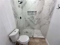 bathroom with tiled shower and toilet