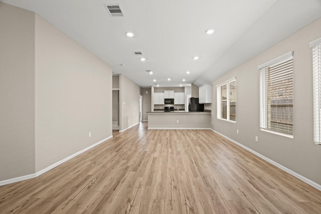 unfurnished living room featuring light wood-style floors, baseboards, and visible vents