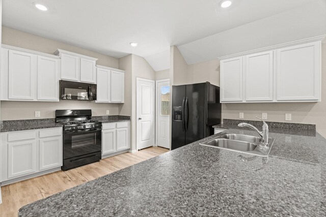 kitchen featuring light wood finished floors, white cabinets, black appliances, a sink, and recessed lighting