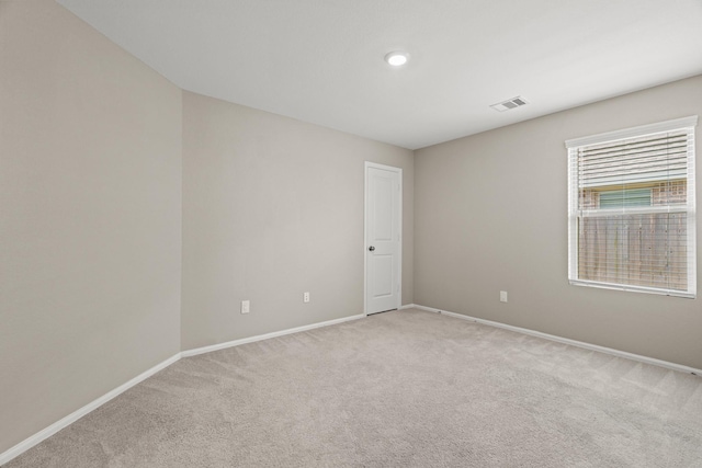 empty room with visible vents, light carpet, and baseboards