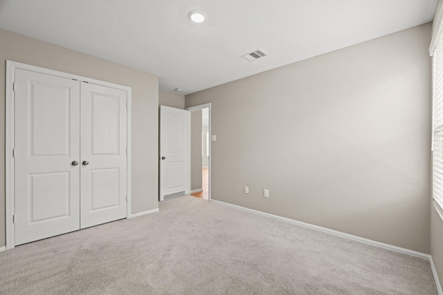 unfurnished bedroom with carpet floors, baseboards, visible vents, and a closet