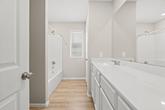 bathroom with shower / bathtub combination, baseboards, wood finished floors, and vanity