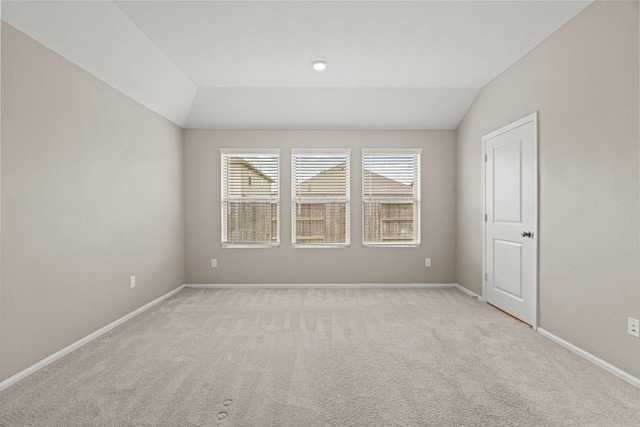 unfurnished room featuring lofted ceiling, light carpet, and baseboards