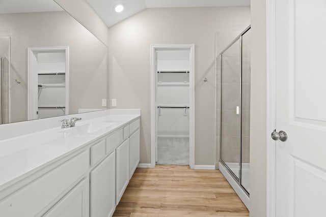 bathroom featuring a shower stall, a walk in closet, wood finished floors, and vanity