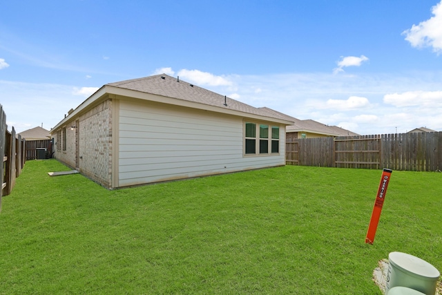 back of property featuring a yard, brick siding, central AC, and a fenced backyard