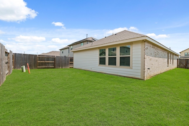 rear view of property featuring a yard, brick siding, and a fenced backyard