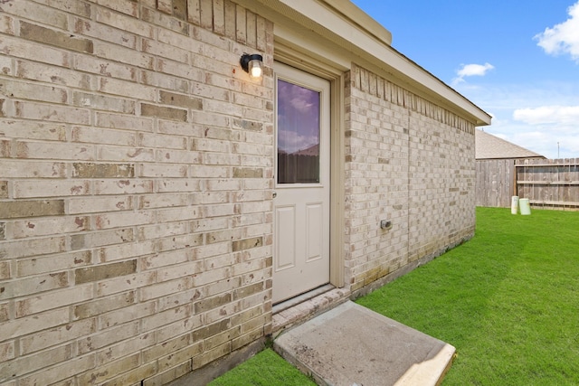 doorway to property with brick siding and fence