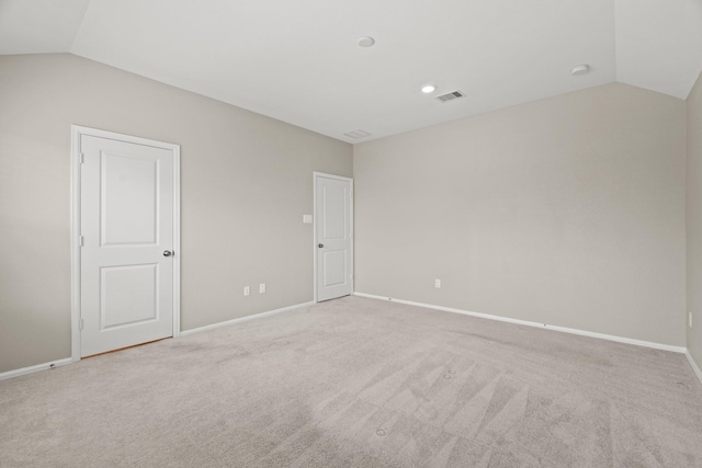 spare room with lofted ceiling, light carpet, visible vents, and baseboards