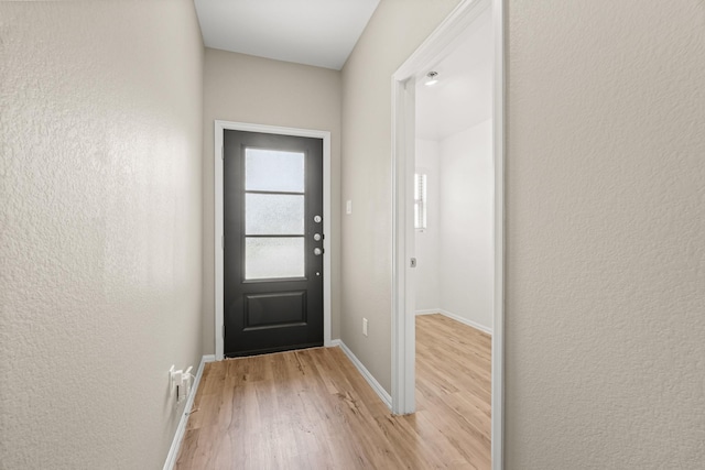 entryway featuring light wood-type flooring, baseboards, and a textured wall