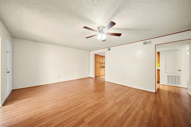 unfurnished room with a textured ceiling, light wood-type flooring, and ceiling fan