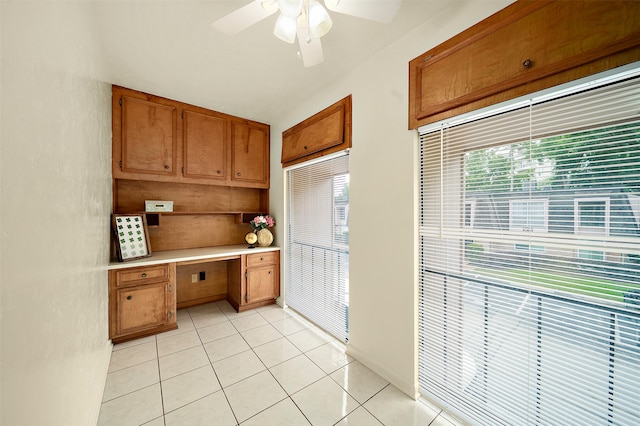 kitchen with light tile patterned flooring, a healthy amount of sunlight, ceiling fan, and built in desk