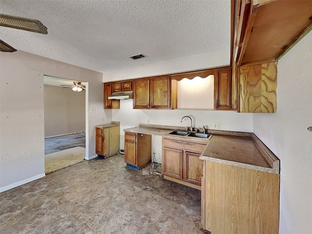 2613 34th Ave N, Texas City, TX 77590 - kitchen with a sink, under cabinet range hood, brown cabinetry, a textured ceiling, and a ceiling fan