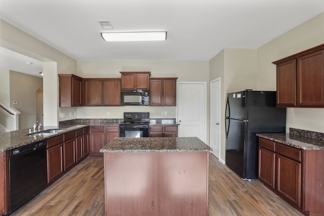 kitchen with black appliances, sink, a kitchen island, dark stone countertops, and dark wood-type flooring